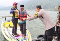 Kapolres Magetan Membantu Wisatawan Turun Dari Speadboat Di Telaga Sarangan.