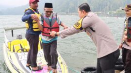 Kapolres Magetan Membantu Wisatawan Turun Dari Speadboat Di Telaga Sarangan.