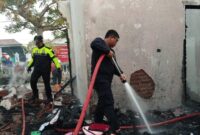 Petugas saat berupaya memadamkan kobaran api di rumah Dinas Puskesmas yang terbakar.