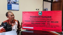 Kabid Penagihan, Evaluasi dan Pelaporan Badan Pengelolaan Keuangan dan Pendapatan Daerah BPKPD Magetan Sumarsono Tunjukan Papan Peringatan Yang Akan Dipasang Di Objek Pajak. 